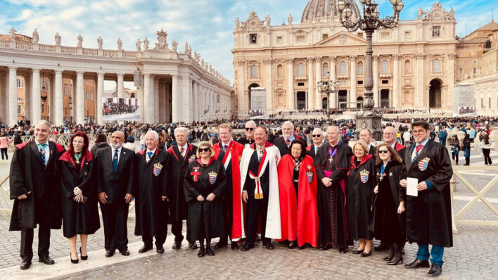 Group of adults dressed in red and black outside large building
