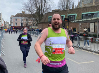 two runners in green vests smiling at the camera