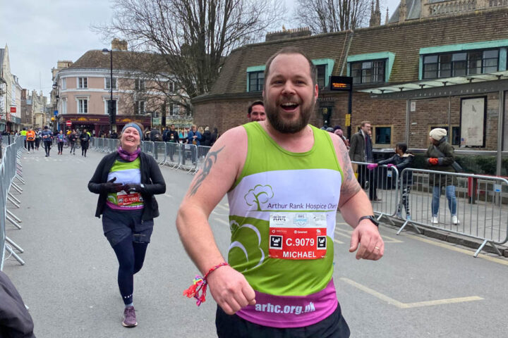 two runners in green vests smiling at the camera