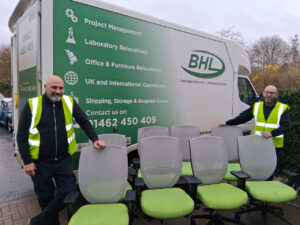 2 males with chairs in front of a van