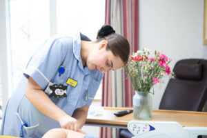 Female nurse caring for patient in bed