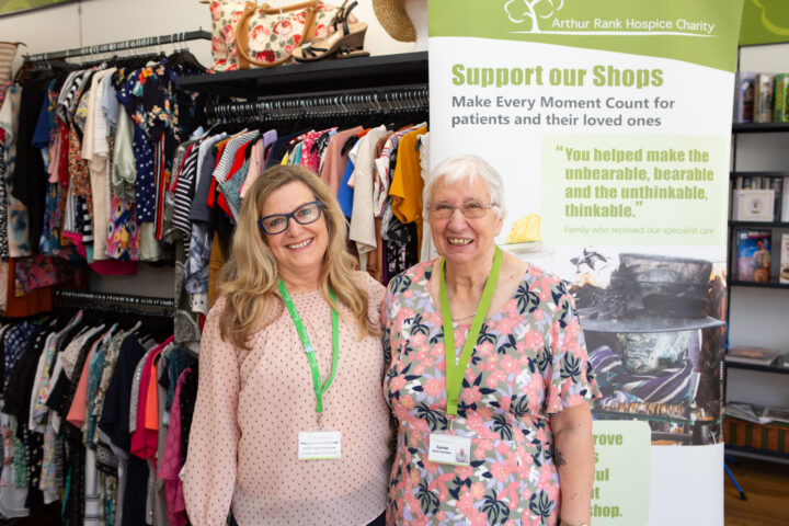 two females standing in front of clothes and banner
