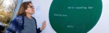 Female looking at green circular mural on white wall