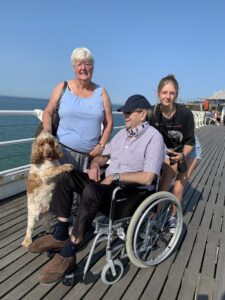 2 females and male in a wheelchair by the beach