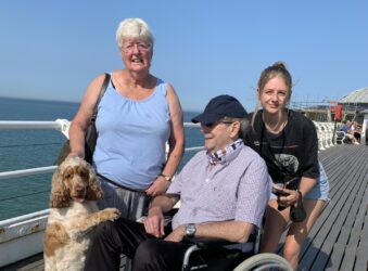 2 females and male in a wheelchair by the beach