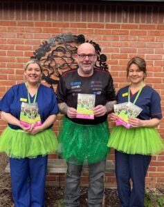 Male dressed in a green tutu with 2 female nurses
