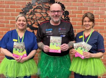 Male dressed in a green tutu with 2 female nurses