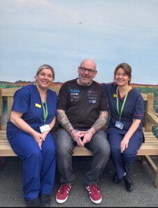 Male with two female nurses sitting on a bench