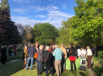 blue sky garden party full of people looking away from camera