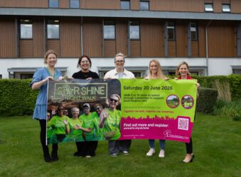 5 females holding a large sign in a garden