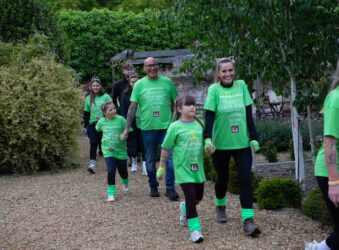 Men, women and children wearing green t-shirts walking