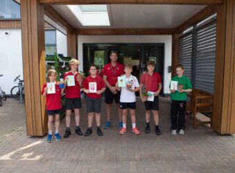 6 children and 1 male adult holding cards and plants