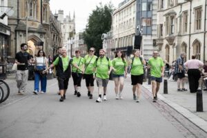 Males and females walking in the street wearing green t-shirts