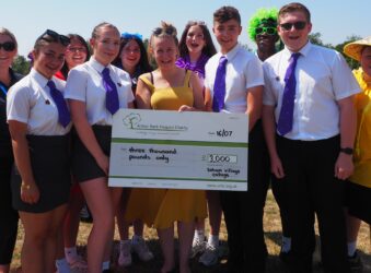 Male and female students in white shirts and ties and a large cheque