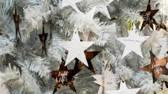 Paper stars on white christmas tree with names on in memory.