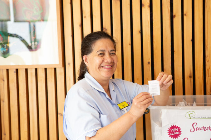 A female nurse with brown hair picking out a winning raffle ticket.