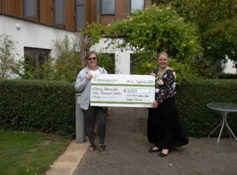 Two females in a garden holding a large cheque