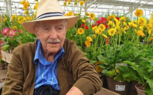Male wearing a hat and flowers behind him